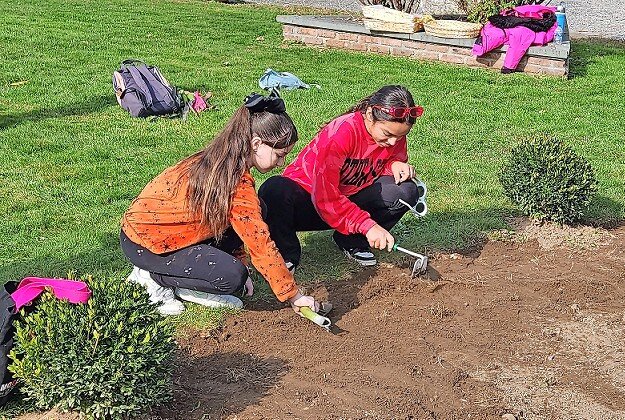 Two young women plan daffodils at the Holocaust Memorial and Tolerance Center in Glen Cove.