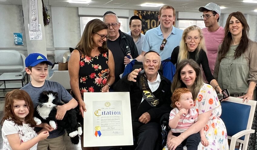 Centenarian Jakub Rybsztajn is surrounded by family and friends at Grandell Rehabilitation and Nursing Center in Long Beach, clockwise from left: Great-grandchildren Bella Rybstein and Isaac Rybstein, Nassau County Deputy Commissioner Debbie Pugliese presenting a proclamation from County Executive Bruce Blakeman, neighbor Ken Moskowitz, son Austin Rybstein, grandson Marc Rybstein, daughter Jennifer Rybstein, grandson Jason Rybstein, daughter-in-law Brenda Rybstein, and Jennifer&rsquo;s daughter-in-law Marissa Rybstein holding great-grandson Benjamin Rybstein. Among those participating in the celebration but not pictured: Son David, and grandchildren Aaron, Josh, Moses and Rebekah.