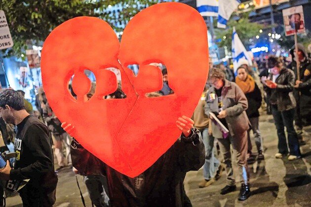 People gather outside of the Kirya base in Tel Aviv on Feb. 20, as the bodies of four Israeli hostages were released from Hamas captivity, including the youngest two, Ariel and Kfir Bibas (a broken heart shows their last name in Hebrew).