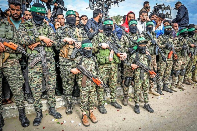 Palestinian children dressed in the Al-Qassam Brigades uniform and carrying weapons participate in a handover of Israeli hostages to the Red Cross, in Deir al-Balah, Gaza on Feb. 8.