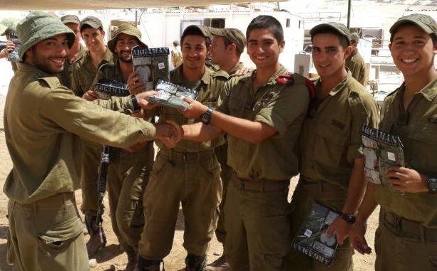 Israeli soldiers holding up packages of undershirts they received from A Package From Home.