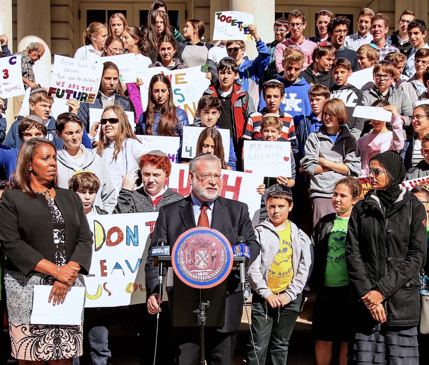 Manhattan Day School students stand behind Orthodox Union Executive Vice President Allen Fagin during a City Hall rally. They asked Mayor deBlasio to include Jewish and Muslim students in the city’s “Free Lunch for All” program, which does not yet offer kosher and halal options. City Councilwoman Leticia James, who spoke at the rally, is at left.