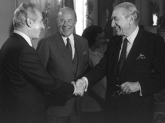 Israeli Prime Minister Shimon Peres (left) shakes hands with U.S. Jewish industrialist Max Fisher at a reception given by U.S. Secretary of State George Shultz (center).