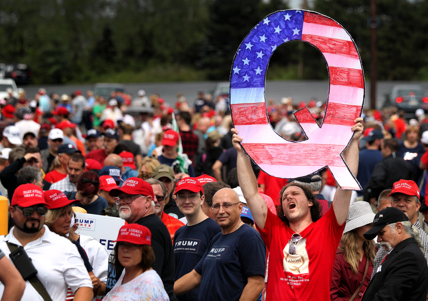 David Reinert holds up a large “Q” sign representing QAnon, a conspiracy group, while waiting in line to see President Donald Trump at a rally in Wilkes-Barre, Pa., on Aug. 2.