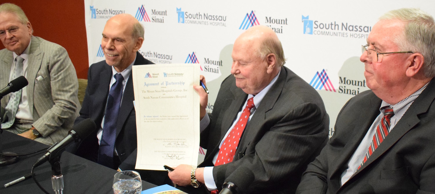 Joseph Fennessy, chairman of the board of South Nassau Communities Hospital, displays the ceremonial partnership agreement signed on Tuesday. Also pictured, from left: Mount Sinai President Dr. Arthur Klein, Mount Sinai CEO Dr. Kenneth Davis, and South Nassau President and CEO Richard Murphy.