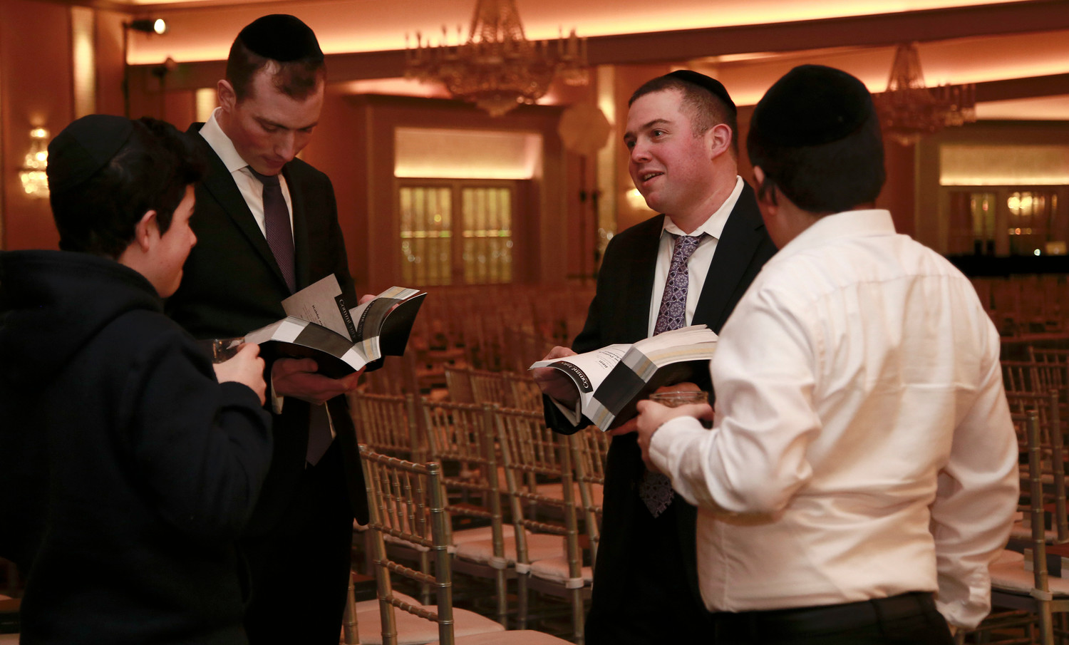 Yossi Riesman, Aaron Guttman, Harry Swambart and Dovid Barkinay browse the gala’s journal, filled with 900 pages of ads placed by Achiezer supporters.