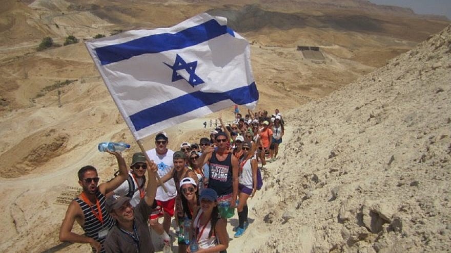 Birthright participants hike up Masada, Israeli flag in hand. 			           Birthright Israel.