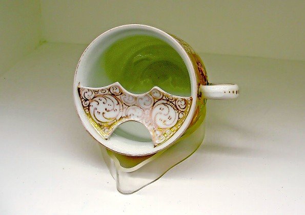 An ornate cup features a mustache-shaped bar in the cup opening designed to protect the facial hair of the coffee drinker.