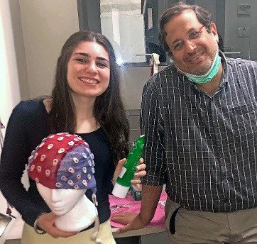 Alyssa Silvera and Dr. David Anaki with an EEG cap, which sits on the head. Using syringes or pipettes, electrode gel is squeezed into the small holes in the cap to connect each electrode to the scalp and transfer the neural impulse.