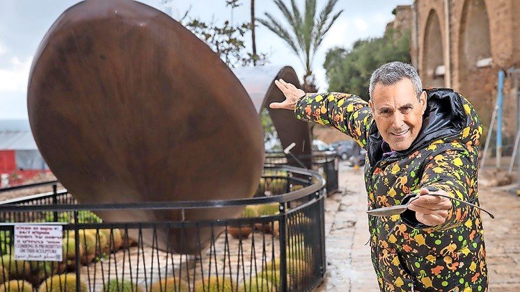Uri Geller next to a giant bent spoon outside his museum in Jaffa.