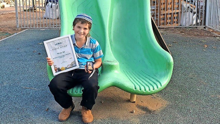 11-year-old Zvi Ben-David holds his certificate of appreciation for good citizenship for turning in an ancient figurine find.
