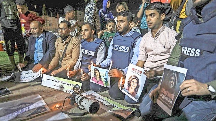 Palestinian journalists take part in a candlelight vigil in the Gaza Strip in memory of Al-Jazeera journalist Shireen Abu Akleh.
