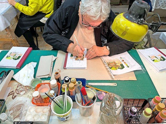Olga, 77, hand illustrates a book cover at Yad LaKashish’s Paper Mache Workshop.