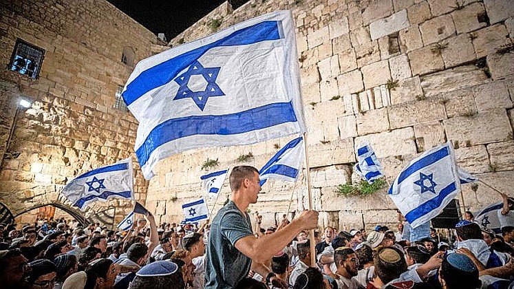 Israelis wave flags at the Western Wall in Jerusalem's Old City on the eve of Jerusalem Day, May 9, 2021.