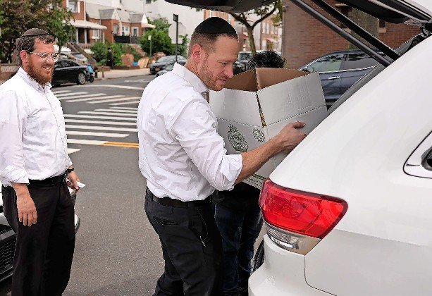 Met Council CEO David Greenfield loads a box of kosher-for-Passover food items into a recipient’s car in 2022.