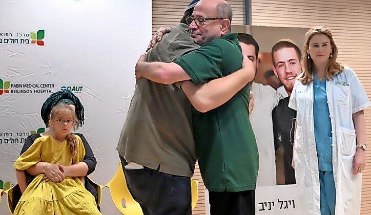 Shalom Yaniv (left), father of terror victims Hallel and Yagel Yaniv, hugs Ron Carmeli, who received a donated cornea, at Beilinson Hospital in Petach Tikvah on June 18.