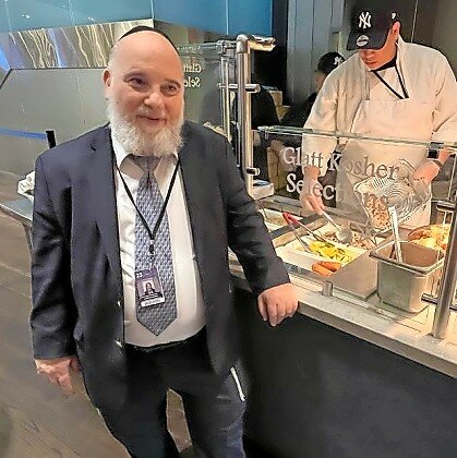 Rabbi Binyomin Steinmetz of the Star-K stands in front of the Legends Suite Kosher Action Station.