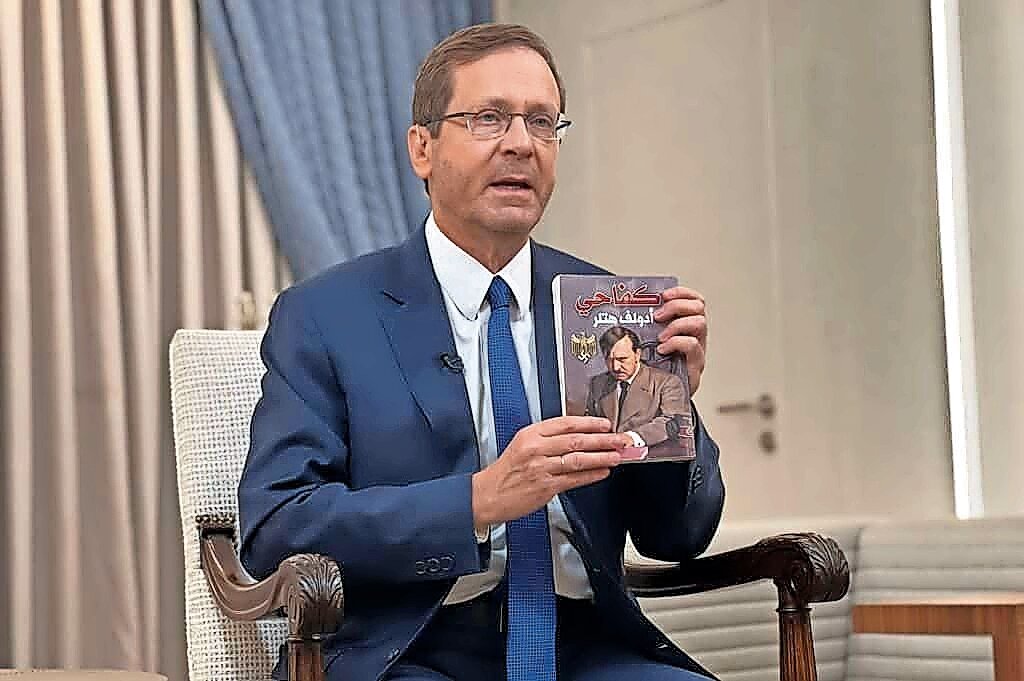 Israeli President Isaac Herzog holds up a copy of an Arabic translation of “Mein Kampf” that was found by IDF troops in a children’s room used as a Hamas terror base in the Gaza Strip, on Nov. 12.