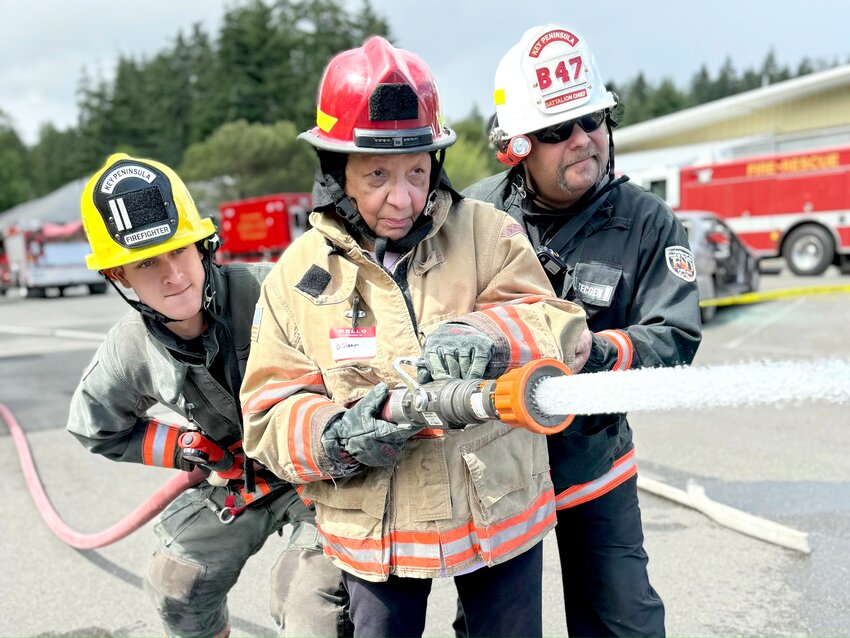 KP Fire Citizen Academy participant Dee Starr, center, in June, backed up by Volunteer FF Garrett Cranford, left, and Battalion Chief Bill Sawaya. The academy is a two-day course introducing residents to basic aspects of being a first responder.