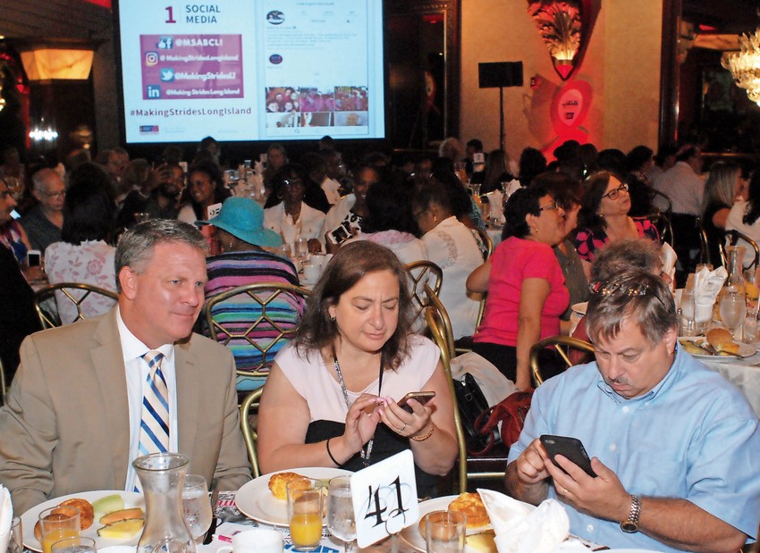 Attendees of the breakfast were asked to join in the American Cancer Society’s social media campaign to promote the Making Strides Walk. At front were, from left, Herald Community Newspapers Advertising Manager Scott Evans, Wantagh-Seaford Editor Eden Laikin and Senior Editor Jeff Bessen. 