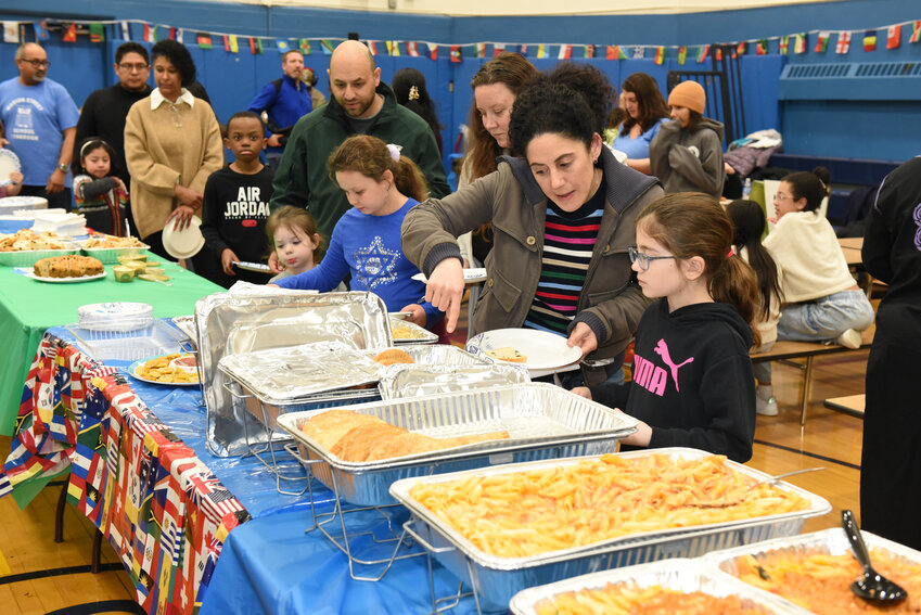 Parents and children lined up to try a variety of cuisines in the school’s gymnasium, all prepared by parents and local businesses.