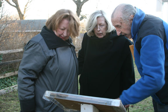 Gabe Parrish, right, vice president of the Historical Society, shows the Sullivan sisters a plaque in the Pagan-Fletcher’s backyard about Curtiss Airfield.
