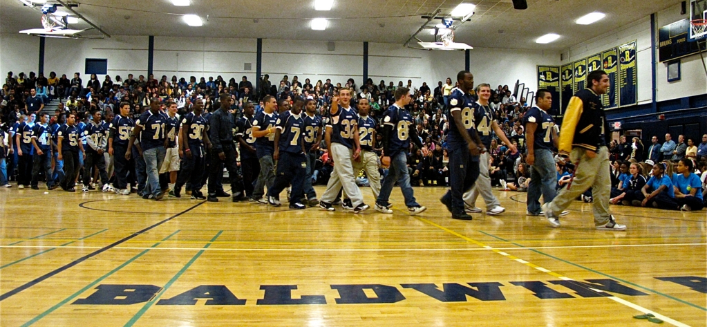 The football team thundered into the pep rally to resounding applause.