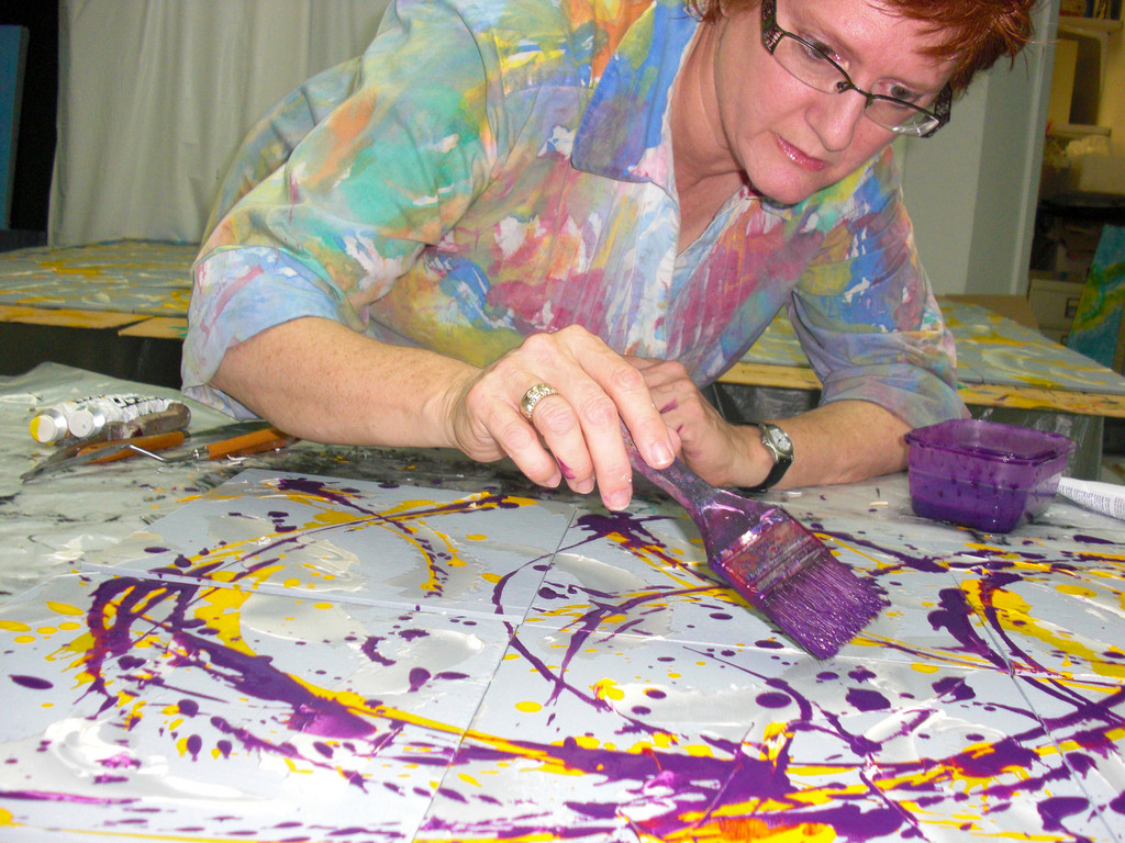 Artist Alli Berman at work on one of her paintings. Her creations are on display at Long Island Children’s Museum, in the exhibition “Swirls, Waves & Puzzles.”