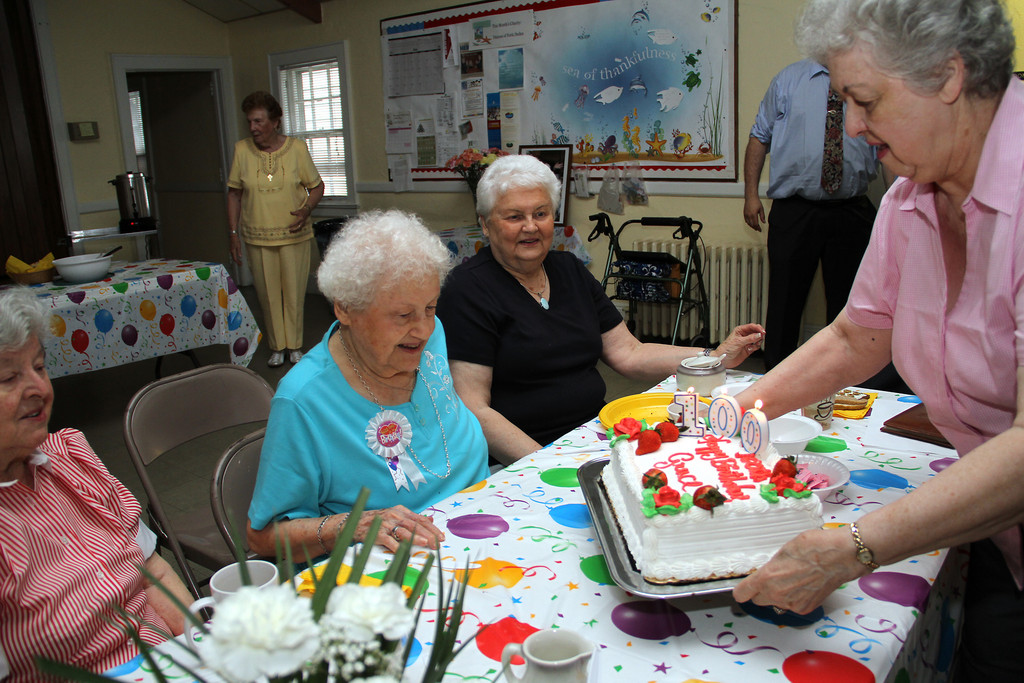 Evelyn Jacobs presents 100th birthday girl Grace Bucking with her cake.