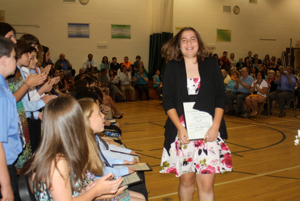 As classmates and family  applaud, seventh-grader Elisabeth De Carmine takes her place among the members of Lynbrook North Middle School’s National Junior Honor Society.