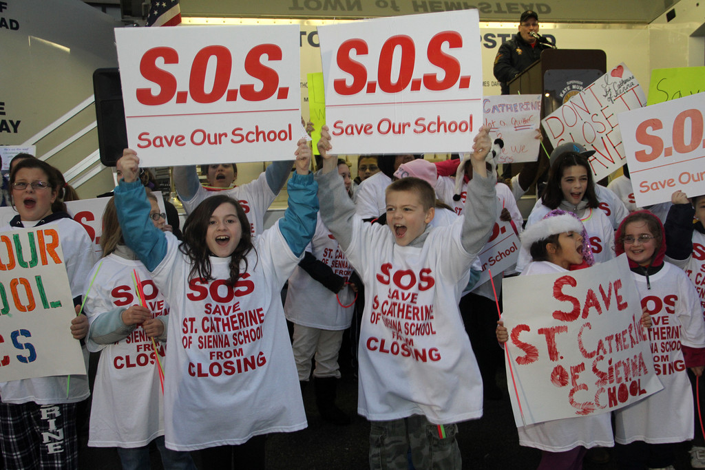 Erin Flood, left, and Matt Alamia held "Save Our School" signs last week.