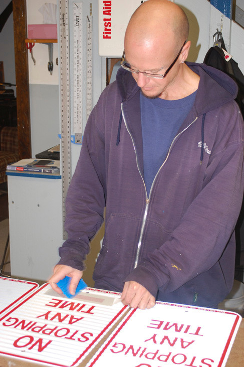Jim Cassidy, supervisor of the Sign Shop, puts the finishing touches on some parking regulation sighs.