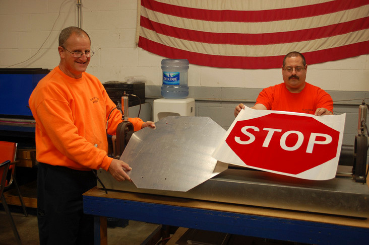 Valley Stream Sign Shop workers Ed Ochman, left, and Mike Field show how a stop sign gets made. There are about 1,200 in the village.
