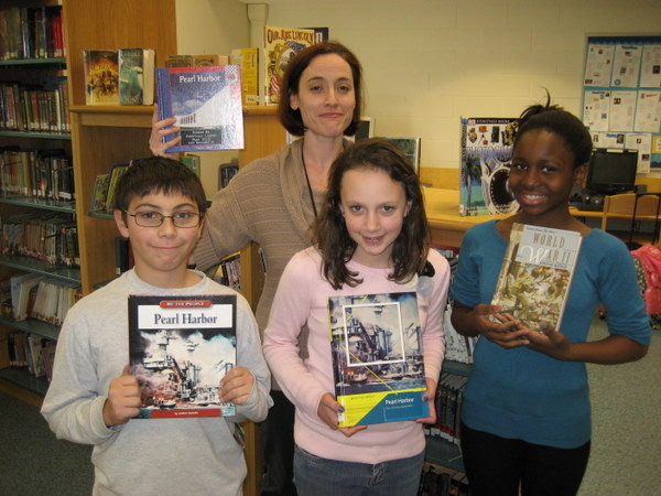 Centre Avenue Elementary School Librarian Petra Schoen, left, with sixth-grade students Peter Wilson, Jade Andruszkiewicz and Aliya Croft, show off books about Pearl Harbor that were donated by the American Legion.