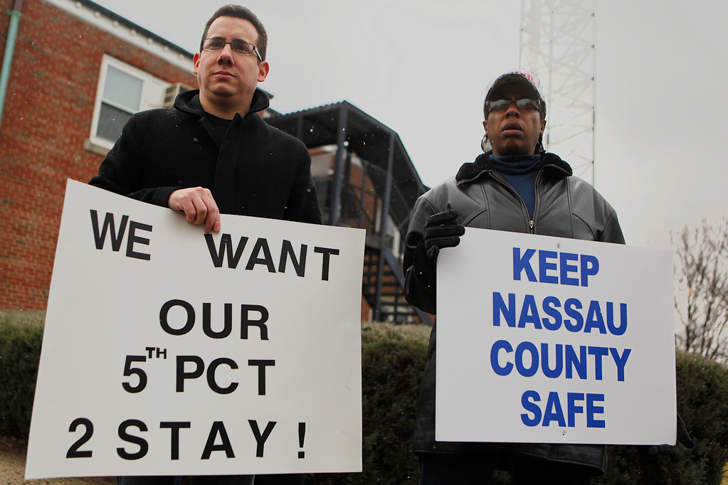 Delphine Godbolt, left, and Bryan Rivera held signs in opposition to the county's 5th Precinct plan on Feb. 11.