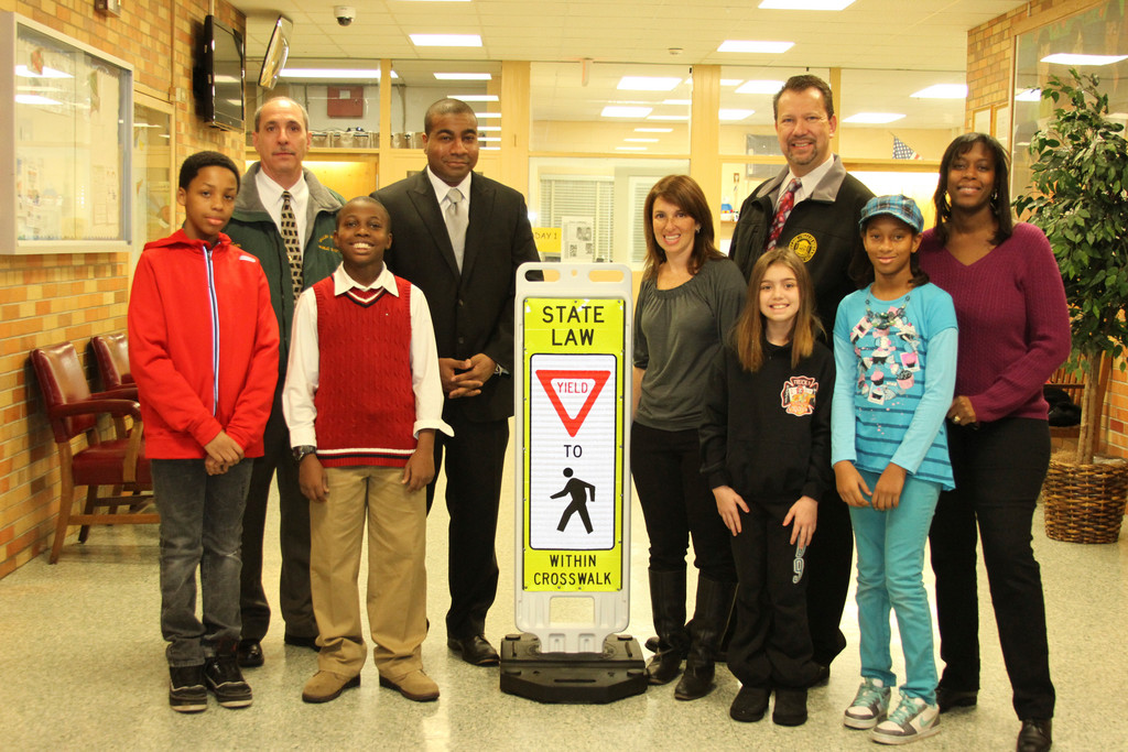 The Village recently donated a sign to Shaw Avenue School to help solve traffic porblems around the building. From left are Isaiah Ryan, Public Safety Director Tom DeSimone, David Fede, Trustee Dermond Thomas, Mayor Ed Fare, Assistant Principal Amy Pernick, Samantha Gipson, Janez Francis and Janice Francis.