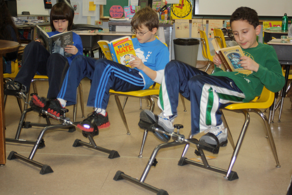 Fourth graders at Lynbrook’s Waverly Park School have been combining exercise with reading in a grant-funded program called “Read and Ride.” From left were Dylan Godley, Jesse Lehman and Jack Hoffman pedaled as they read.