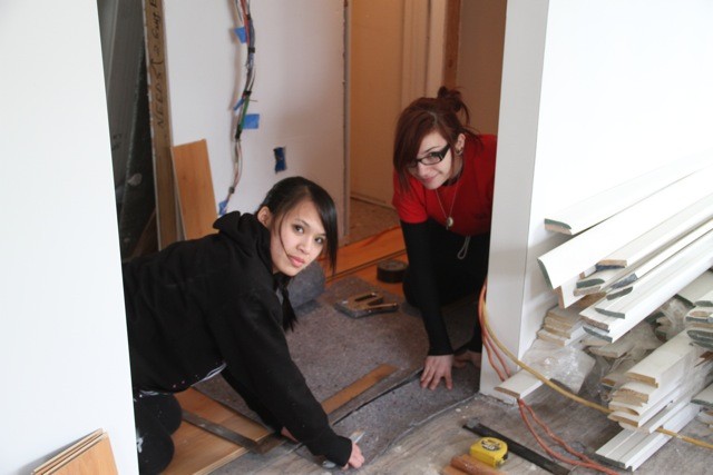 Cap: Victoria Hanson, left, and Melissa Voellm, of Ambassador Girl Scout Troop 1422, installed a Pergo floor in the hallway of the Mineola home.