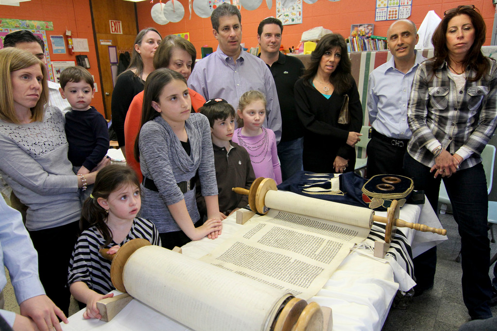 Congregants gathered around the Torah to learn about the interesting writing history.