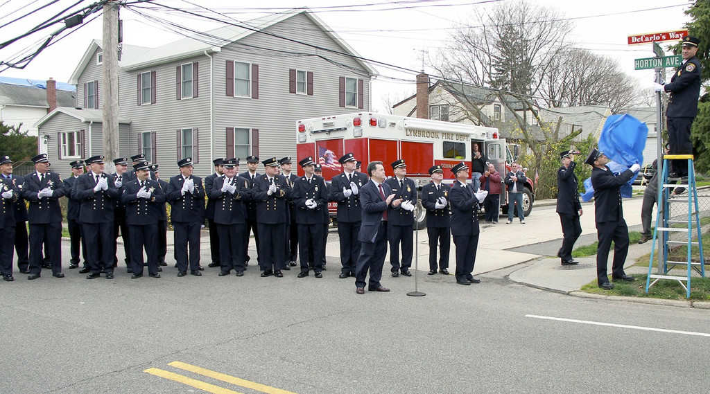 Members of the Lynbrook Fire Department and Mayor Bill Hendrick, center, applauded as the new sign was unveiled.