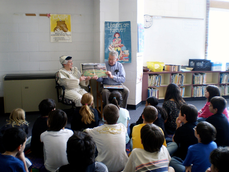 Jane Brezenoff dressed for the part when she and her husband read a sports book to the students. Below, Mr. Piccarella reads his selection.