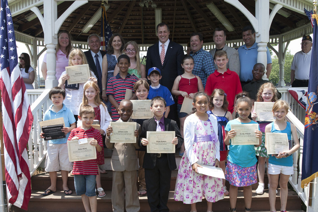 The winners of the contest “What the American Flag Means to You” were congratulated by Assemblyman Brian Curran, top center, and village and school officials.