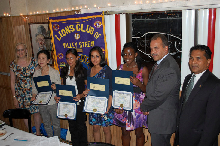 The Lions Club presented four local students with scholarships last Thursday night. From left are Secretary Wendy Fredericks, Young Sin representing her daughter, Sara, recipients Madona Gadalla, Silvia Arora and Sharifa Davis, Lions Club President Jose Pastrana and Treasurer Channan Persaud.