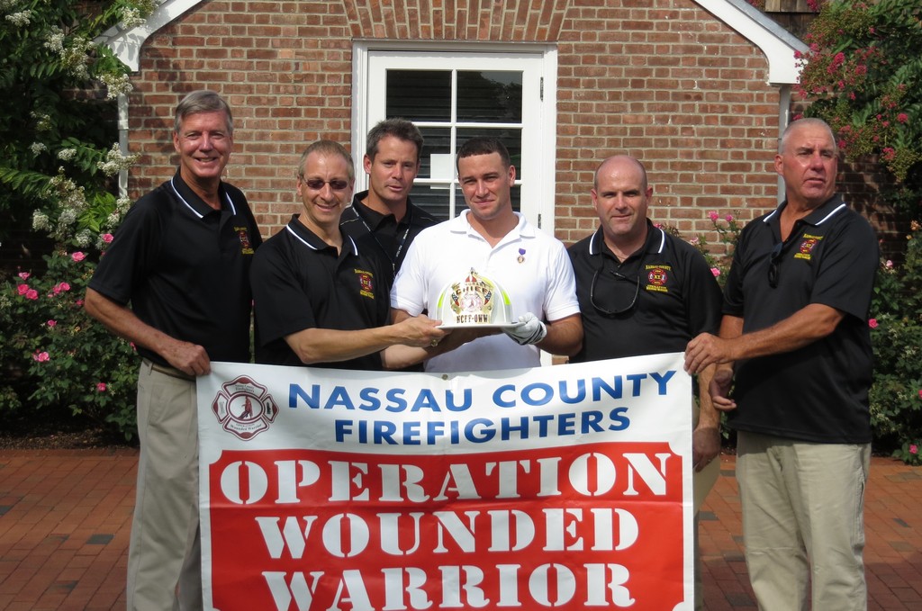 Marine Kevin Vaughan, center, received a helmet, making him an honorary Nassau County fire chief. Joining in the presentation at the Barclay’s Golf Tournament at Bethpage were, from left, firefighters Steve Grogan of Lynbrook, and Mike Kushner of Stewart Manor, Steve Kupcha of the PGA’s Community Military Outreach, and firefighters Tom Smith of New Hyde Park and Brian Gurr of Bethpage.
