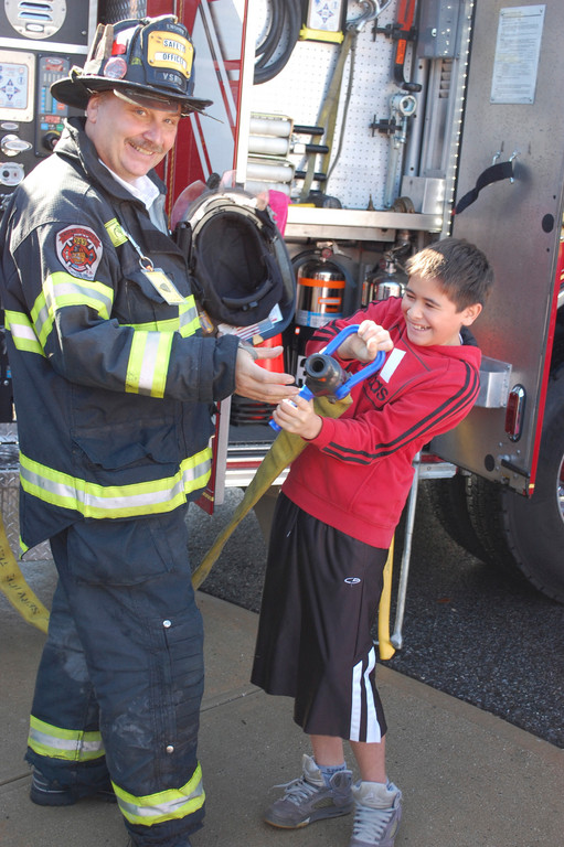Kevin Paez, a sixth-grader at the Robert W. Carbonaro School, checked out the equipment that real firefighters use with Valley Stream Fire Department Safety Officer Michael Laxton on Oct. 10.