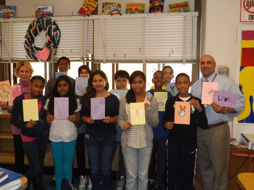 Students in Lynne Pravda’s art classes at Memorial Junior High School made cards for the people of Newtown, Conn. to show their support of the grief-stricken community. Pictured with Pravda, top left, are a group of seventh graders displaying their work and Memorial Principal Anthony Mignella, right.