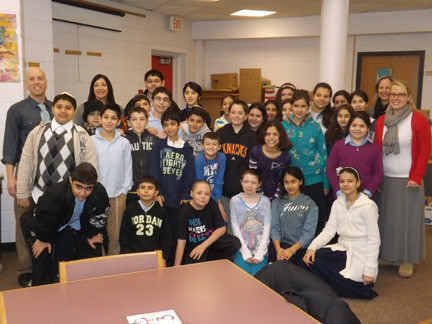 Brian Croce/Herald
The Jewish Institute of Queens raised money, purchased needed items and personally delivered those items to Rhame Avenue Elementary School on Monday. Pictured are students, faculty members and administrators from both schools in Rhame’s storm-damaged library.