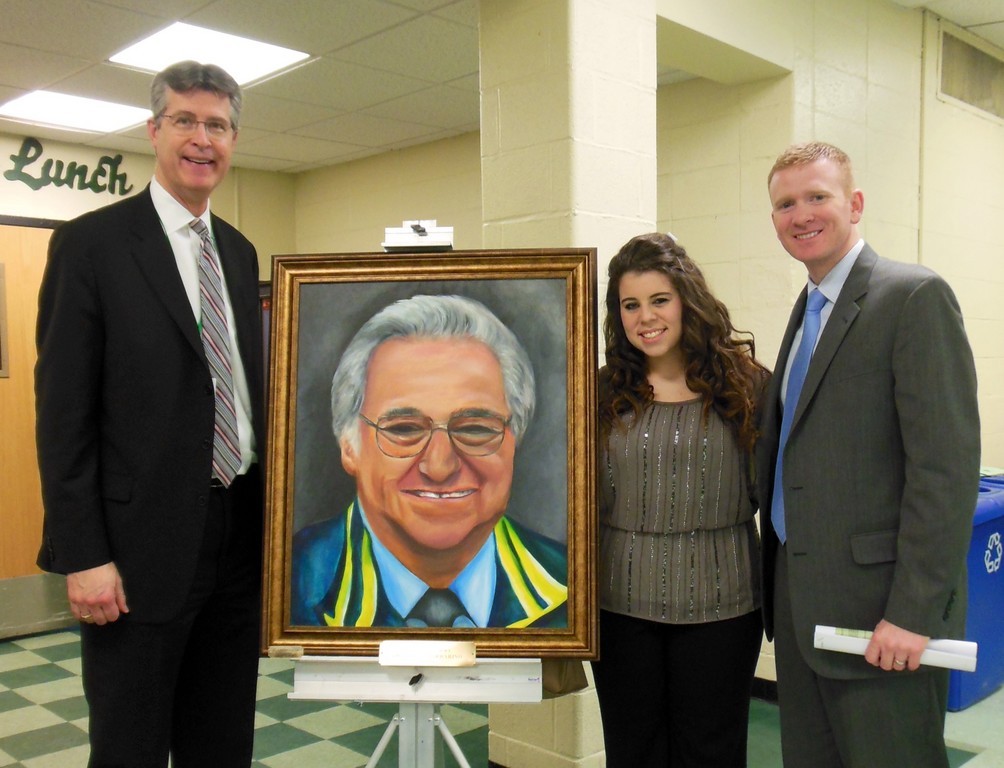 Jen Varvaro, a senior at Lynbrook High School, showed off her portrait of the much-beloved Dr. Santo Barbarino at the Feb. 6 Board of Education meeting. She was joined by Principal Joe Rainis, left, and Assistant Principal Matt Sarosy.
