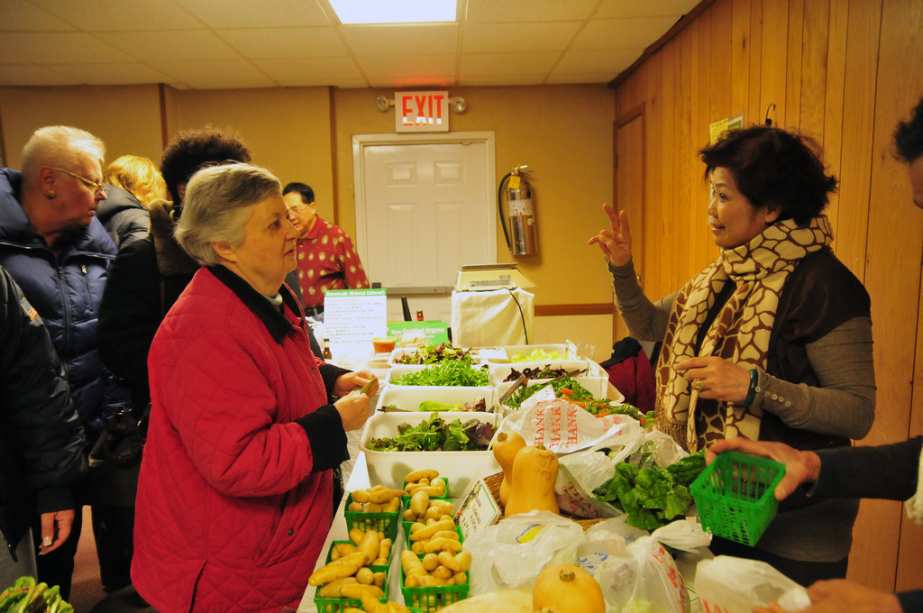Ann Mott bought fresh greens from Julie Yen. Yen also sold winter squashes and fingerling potatoes.