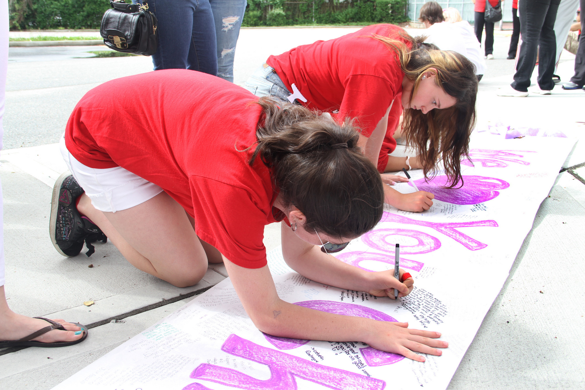 Lauren Becker and Katie Walsh signed the banner for Chris before the funeral procession passed by South High School on June 8.